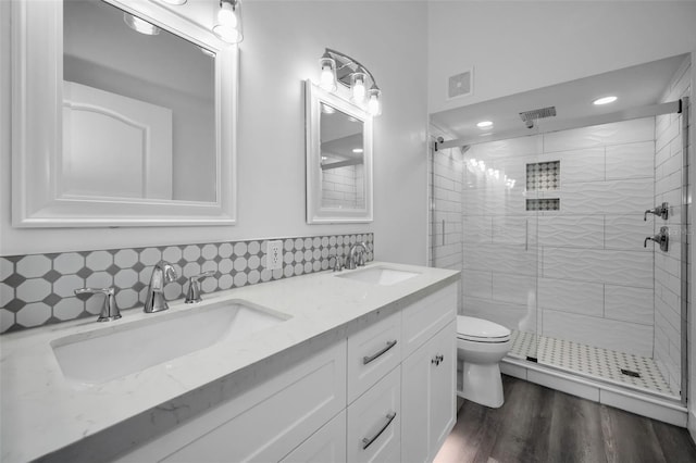 bathroom with hardwood / wood-style floors, toilet, walk in shower, and tasteful backsplash