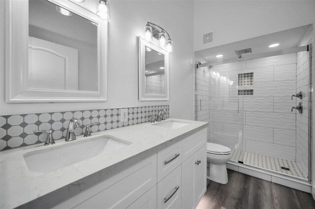 2292 Austrian Ln Unit 34, Clearwater, FL 33763 - bathroom featuring a stall shower, double vanity, toilet, wood finished floors, and decorative backsplash