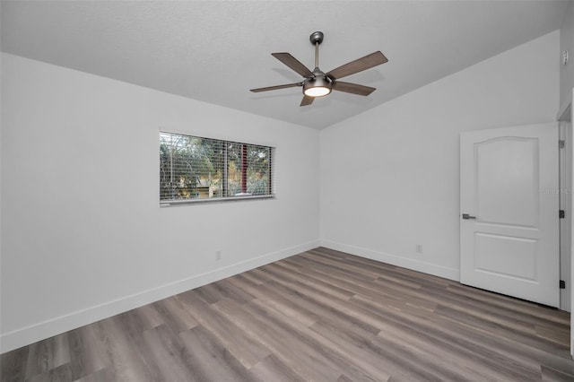 spare room with a textured ceiling, ceiling fan, hardwood / wood-style floors, and vaulted ceiling