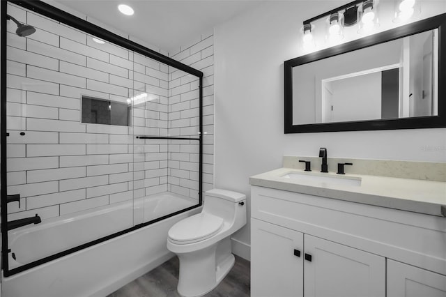 full bathroom with hardwood / wood-style flooring, toilet, combined bath / shower with glass door, and vanity