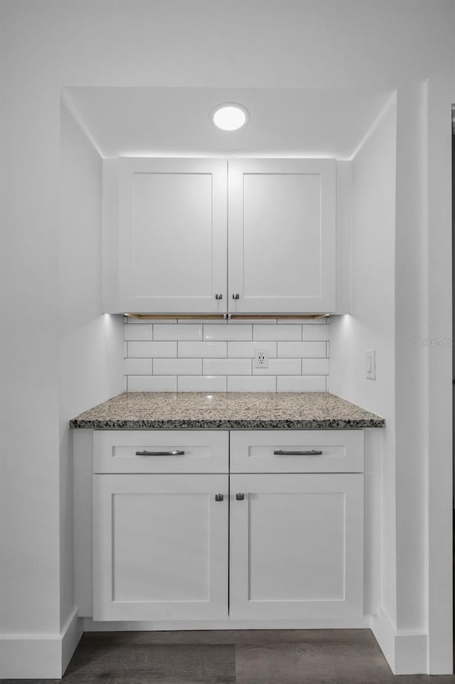 kitchen with light stone countertops, backsplash, and white cabinetry