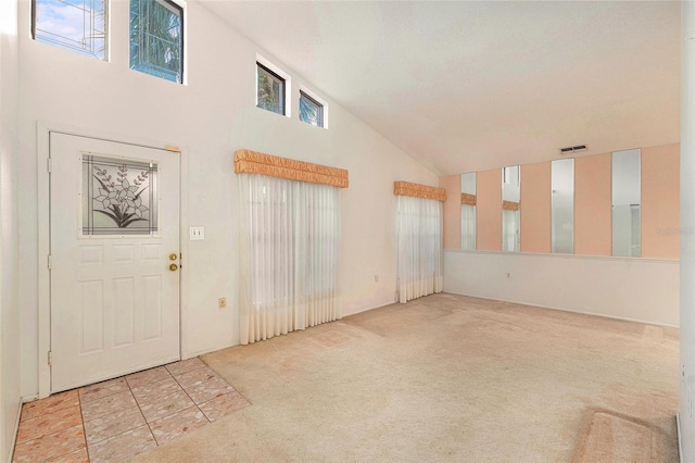 carpeted foyer entrance featuring high vaulted ceiling