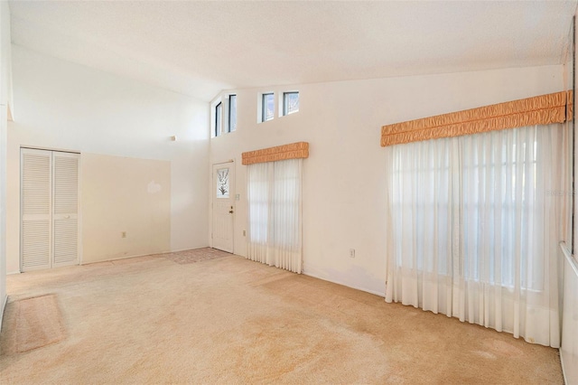 carpeted empty room featuring high vaulted ceiling and a textured ceiling