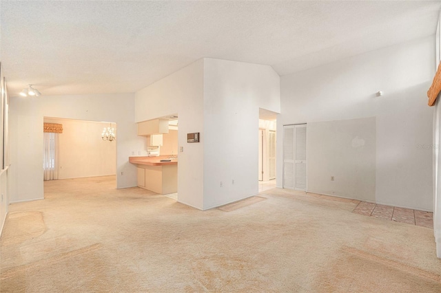 unfurnished living room with a textured ceiling, light colored carpet, and high vaulted ceiling