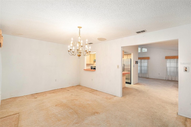 carpeted empty room featuring a chandelier and a textured ceiling