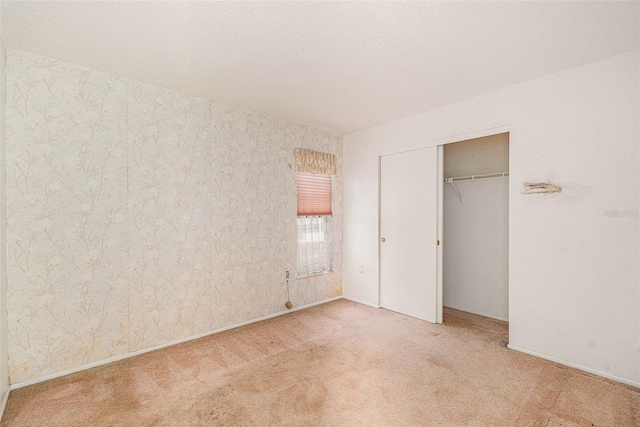 unfurnished bedroom featuring a textured ceiling, light colored carpet, and a closet