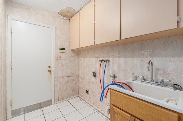 laundry room featuring cabinets, washer hookup, a textured ceiling, sink, and light tile patterned flooring