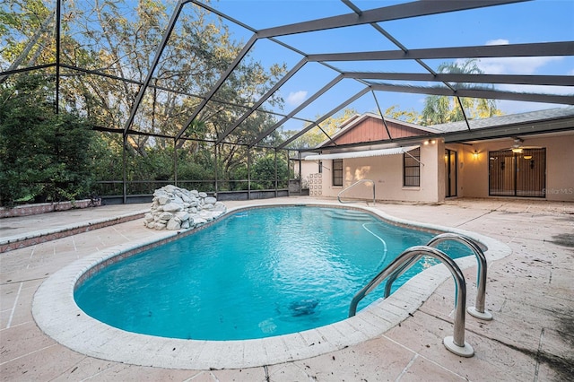 view of swimming pool featuring glass enclosure, ceiling fan, and a patio