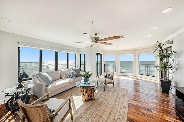 living room with crown molding, a water view, wood-type flooring, and ceiling fan