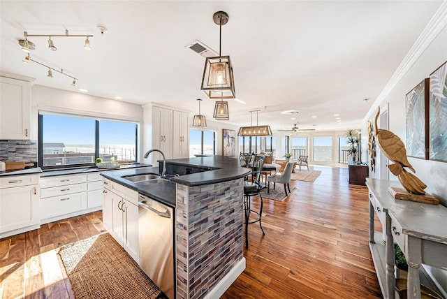 kitchen featuring sink, hanging light fixtures, light hardwood / wood-style flooring, stainless steel dishwasher, and a kitchen island with sink