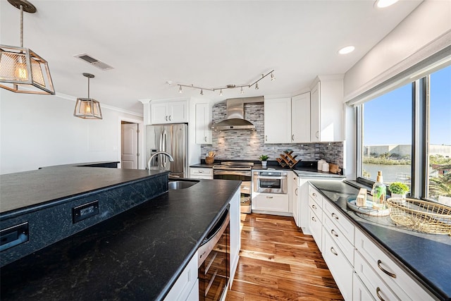 kitchen with white cabinets, sink, wall chimney exhaust hood, light wood-type flooring, and decorative light fixtures