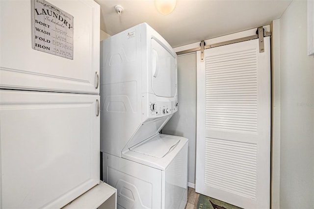 washroom featuring a barn door and stacked washer and clothes dryer