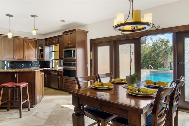 kitchen featuring sink, a breakfast bar area, pendant lighting, stainless steel appliances, and backsplash