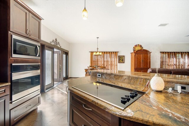 kitchen featuring dark brown cabinetry, appliances with stainless steel finishes, light stone countertops, and hanging light fixtures