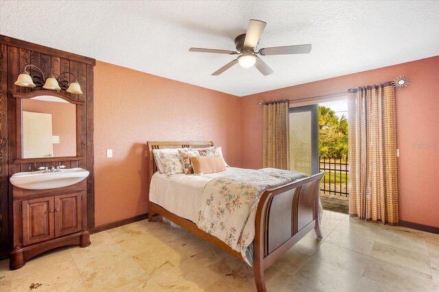 bedroom with ceiling fan, sink, a textured ceiling, and access to outside