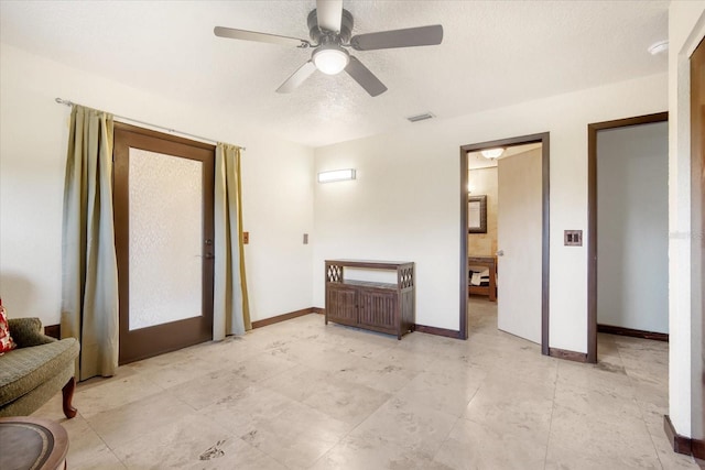 interior space with ceiling fan and a textured ceiling