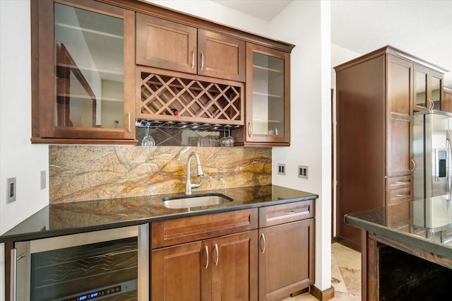 bar featuring sink, stainless steel fridge, wine cooler, backsplash, and dark stone counters