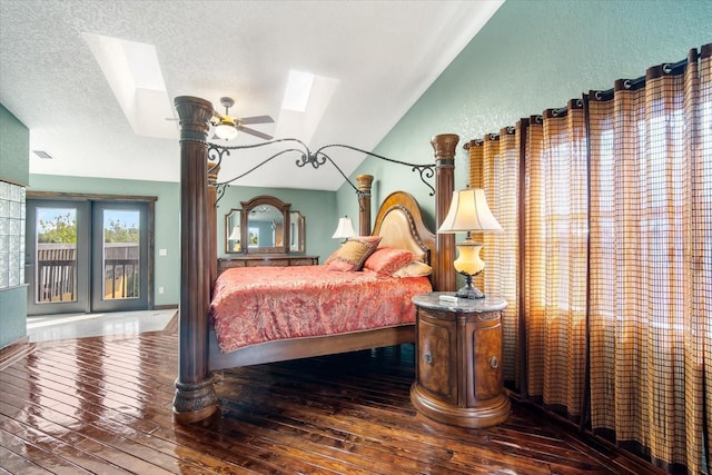 bedroom featuring wood-type flooring, lofted ceiling with skylight, a textured ceiling, and access to outside