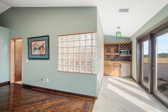 kitchen with vaulted ceiling, hardwood / wood-style floors, and dishwashing machine