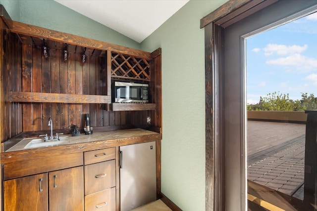 kitchen featuring tile counters, sink, vaulted ceiling, and appliances with stainless steel finishes