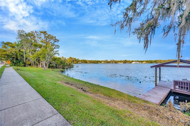 view of dock with a lawn and a water view