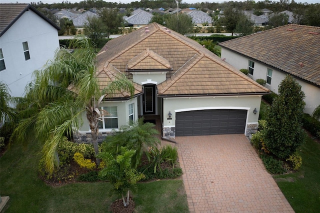 12241 Perennial Pl, Bradenton, FL 34211 - view of front of home with an attached garage, stone siding, a tile roof, and decorative driveway
