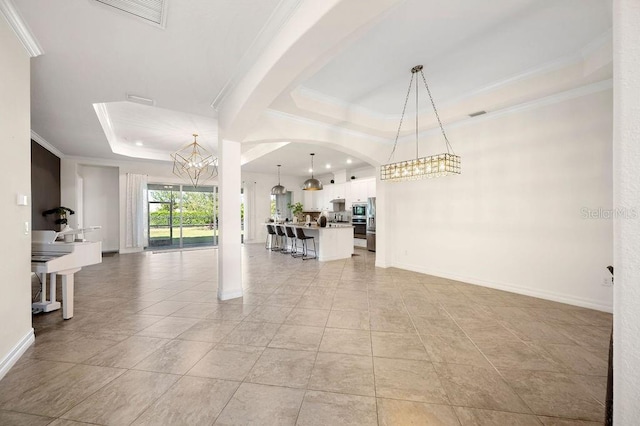 unfurnished living room featuring a raised ceiling, light tile patterned floors, a notable chandelier, and ornamental molding