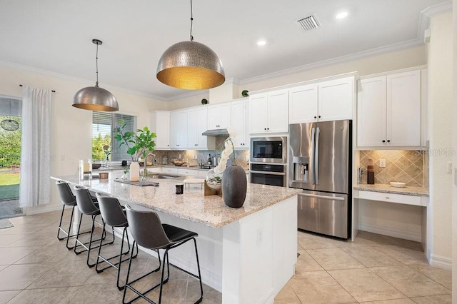 kitchen with white cabinets, decorative light fixtures, stainless steel appliances, and a center island with sink