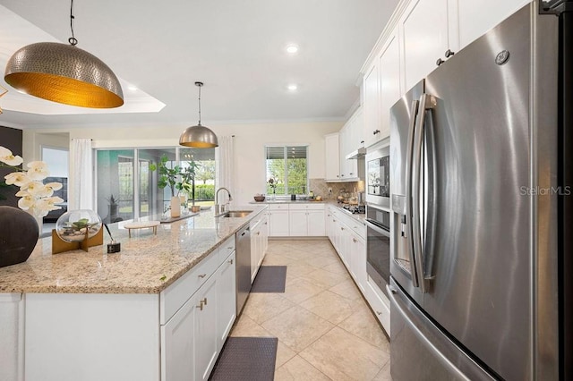 kitchen featuring light stone countertops, white cabinets, hanging light fixtures, and appliances with stainless steel finishes