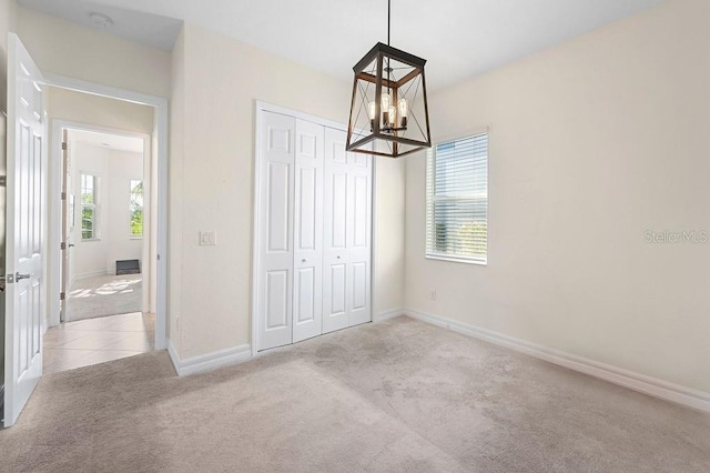 interior space with a closet, light colored carpet, and a notable chandelier