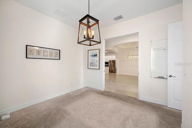 carpeted empty room featuring an inviting chandelier