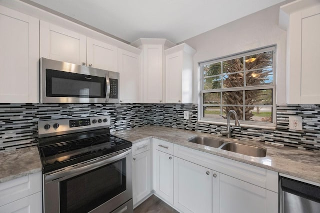 kitchen with backsplash, white cabinetry, sink, and stainless steel appliances