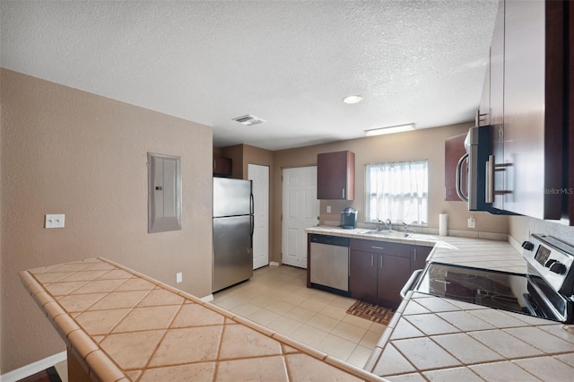 4148 Rudder Way, New Port Richey, FL 34652 - kitchen with appliances with stainless steel finishes, tile countertops, electric panel, a textured ceiling, and a textured wall