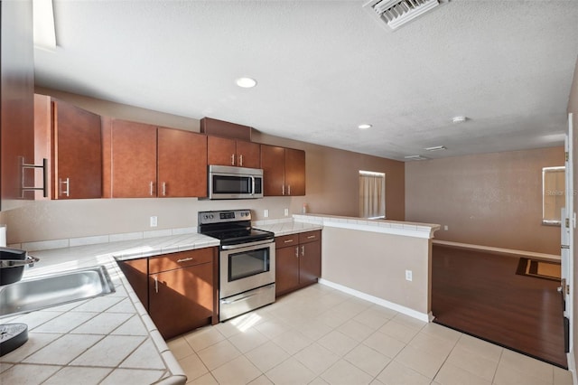 4148 Rudder Way, New Port Richey, FL 34652 - kitchen with stainless steel appliances, tile counters, recessed lighting, a peninsula, and light tile patterned floors