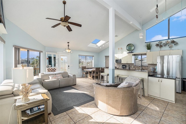 living room with a skylight, ceiling fan, high vaulted ceiling, and light tile patterned flooring