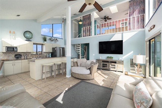 living room with beam ceiling, high vaulted ceiling, light tile patterned floors, and sink