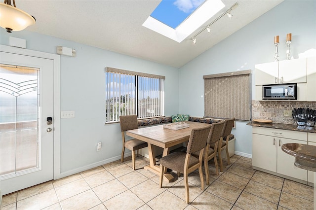 tiled dining space featuring lofted ceiling with skylight