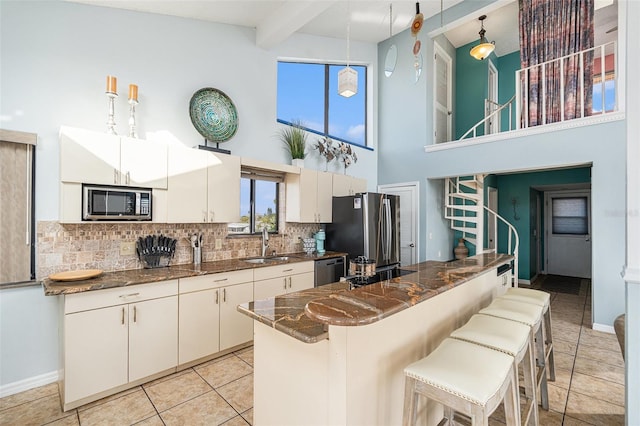 kitchen with beam ceiling, stainless steel appliances, plenty of natural light, and hanging light fixtures