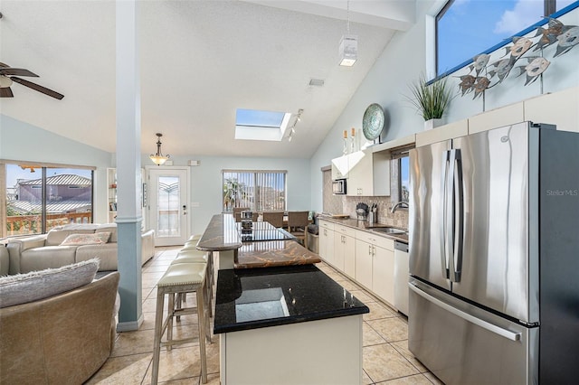 kitchen featuring white cabinetry, sink, ceiling fan, a kitchen bar, and appliances with stainless steel finishes