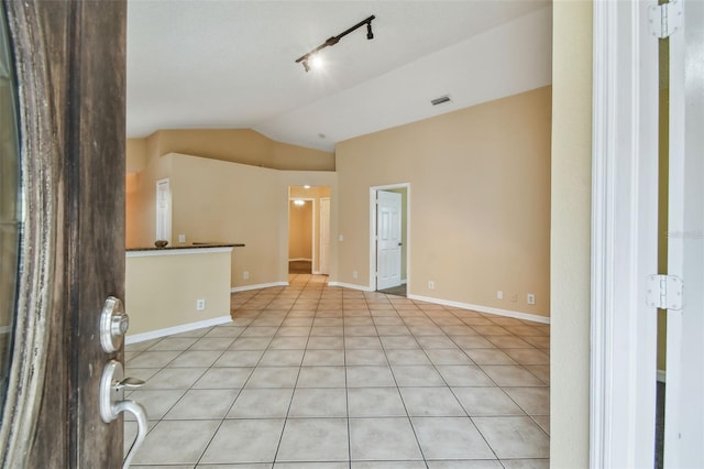 unfurnished room with light tile patterned flooring, lofted ceiling, and rail lighting