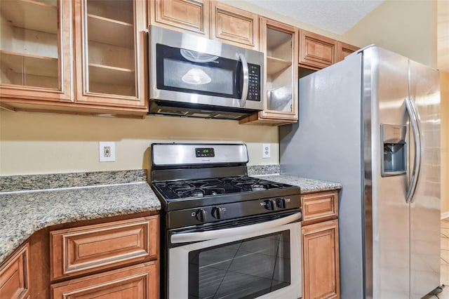 kitchen with light stone counters, stainless steel appliances, and a textured ceiling