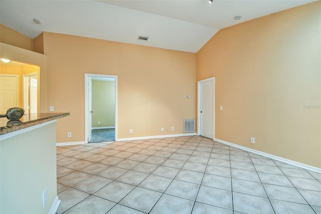 empty room with light tile patterned flooring and lofted ceiling