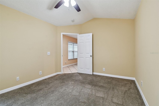 carpeted spare room with ceiling fan, a textured ceiling, and vaulted ceiling