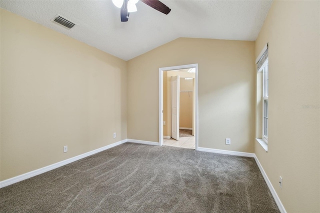 carpeted spare room with ceiling fan, a textured ceiling, and vaulted ceiling