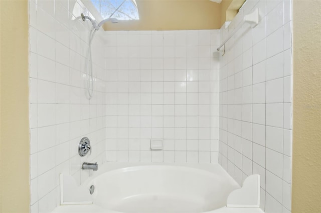 bathroom featuring toilet and tiled shower / bath