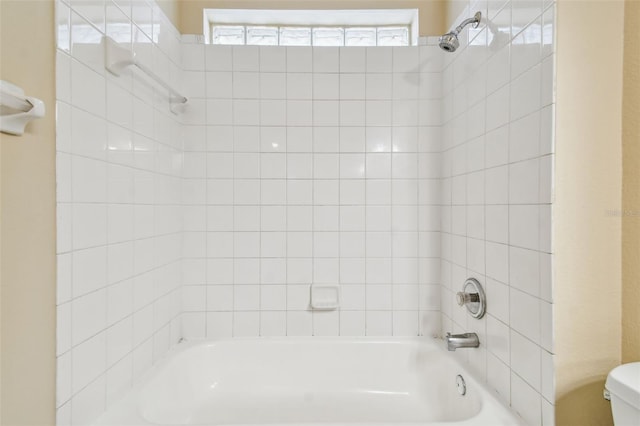 bathroom featuring tiled shower / bath, toilet, and a wealth of natural light