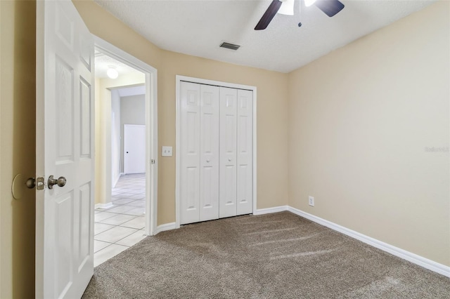 unfurnished bedroom with ceiling fan, a closet, light carpet, and a textured ceiling