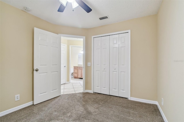 unfurnished bedroom featuring a textured ceiling, ceiling fan, light carpet, and a closet