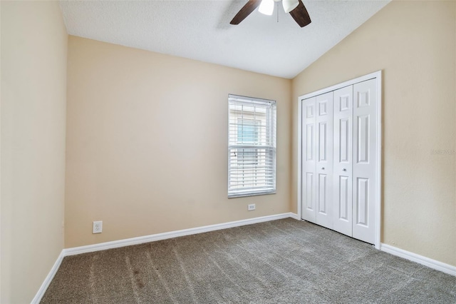 unfurnished bedroom with ceiling fan, carpet floors, a textured ceiling, lofted ceiling, and a closet