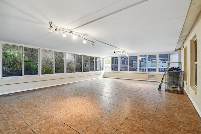 unfurnished sunroom with a wall mounted air conditioner and a healthy amount of sunlight